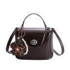 Damen Mini-Handtasche im elegant geschwungenen Design mit spielerischem Anhänger