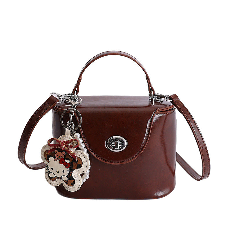 Damen Mini-Handtasche im elegant geschwungenen Design mit spielerischem Anhänger